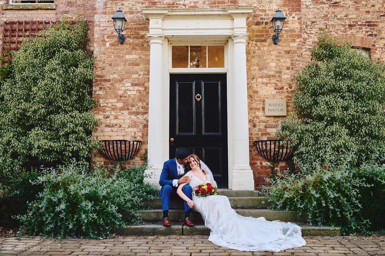 Bride and groom sitting on step and surrounded by beautiful gardens
