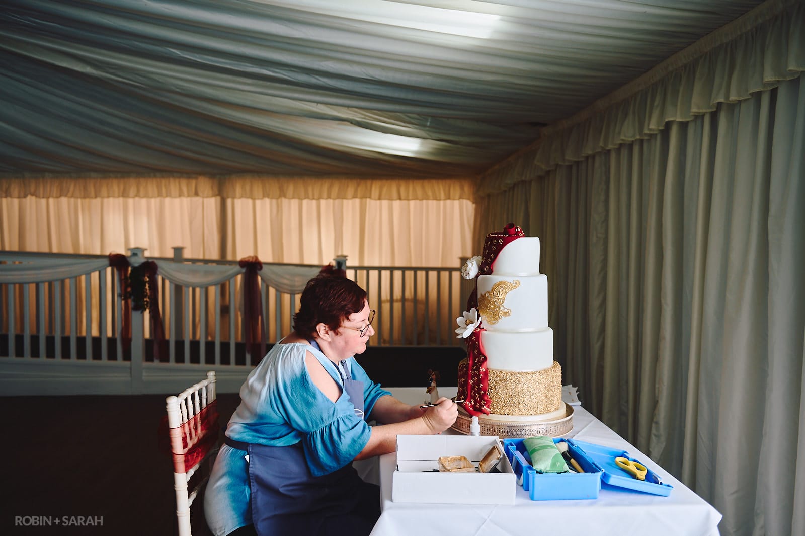 Cake artist puts finishing touches to beautiful cake for fusion wedding