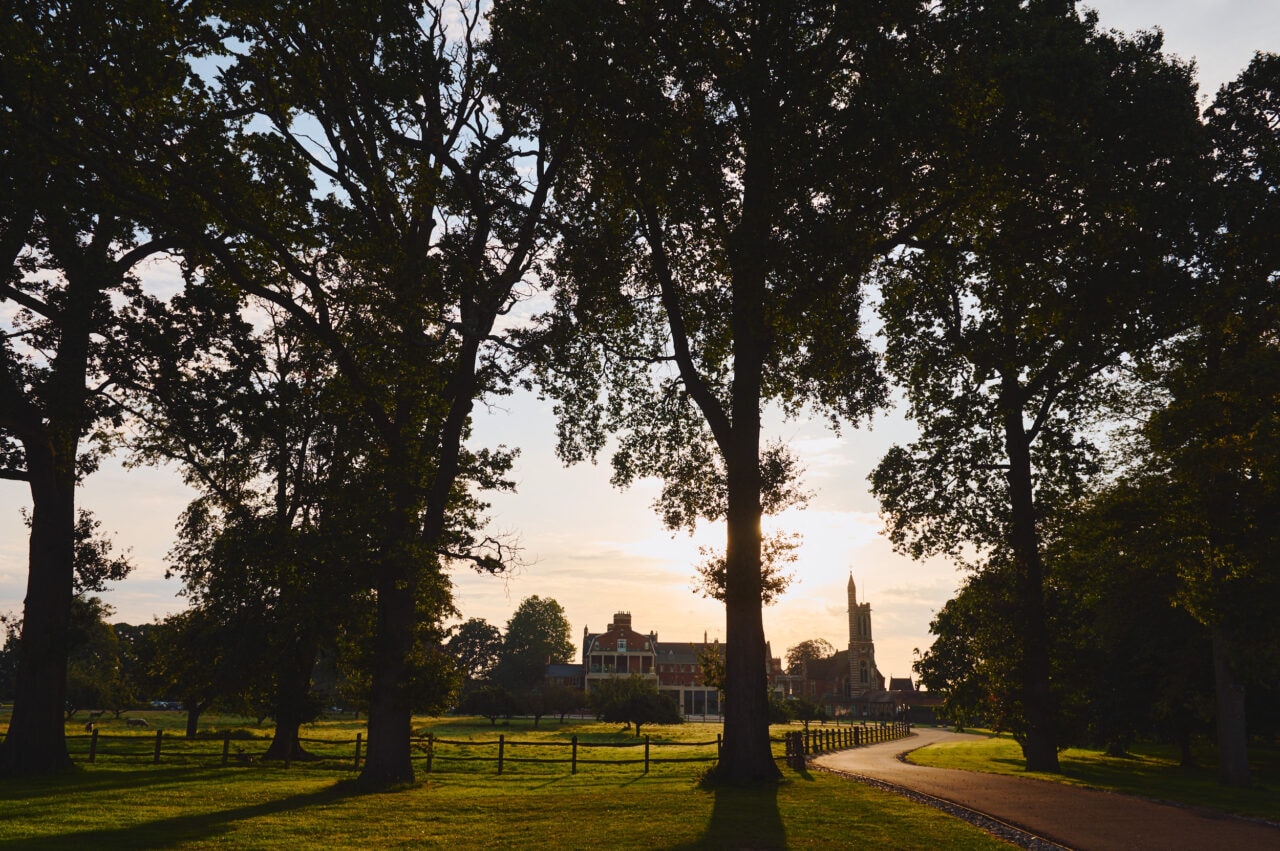 Stanbrook Abbey viewed through trees at sunrise