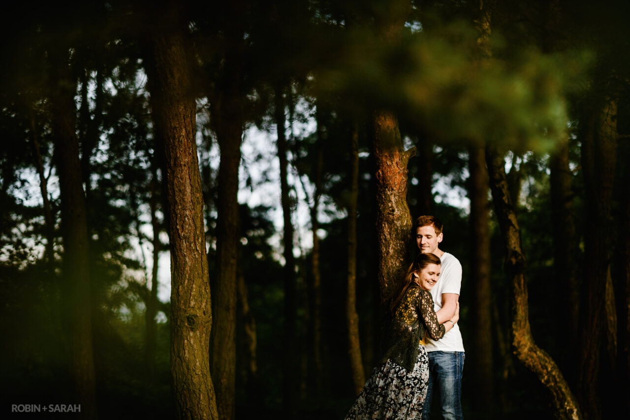 Couple hug under trees on hilltop location