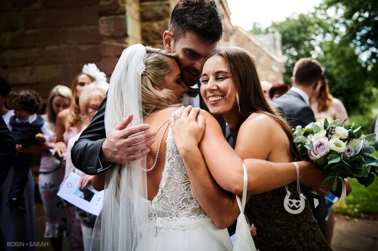 Bride hugs two friends after church wedding