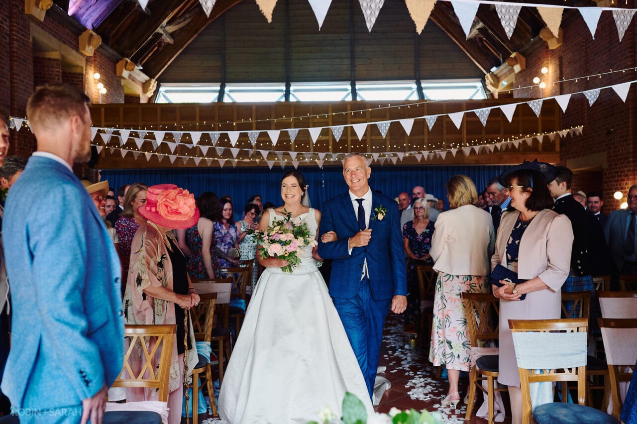 Bride beaming as she walks up aisle for wedding ceremony