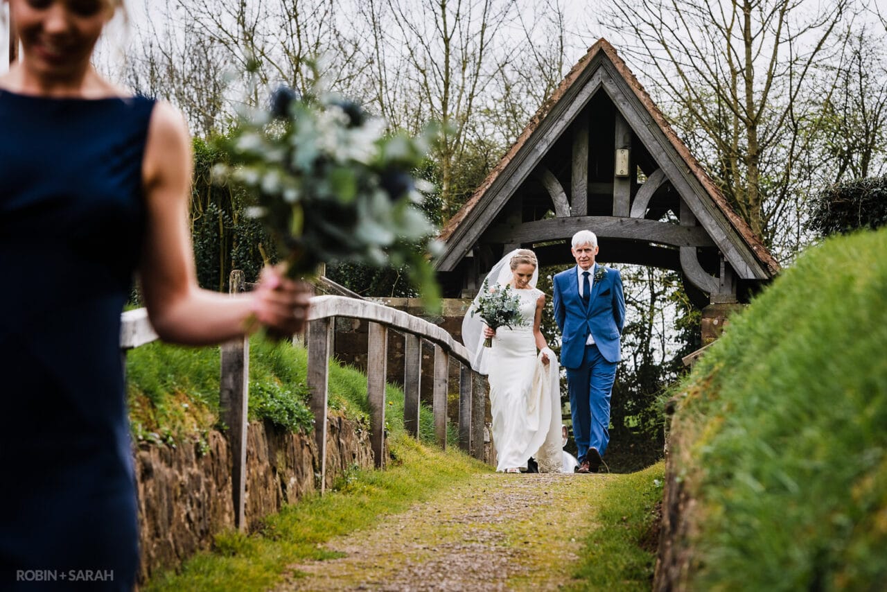 Bride and father walk to church for wedding ceremony