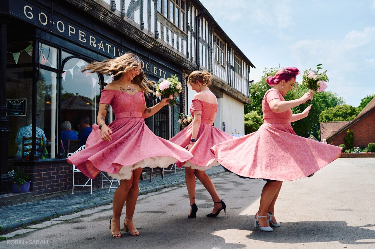 Three bridesmaids in matching pink dresses spin around
