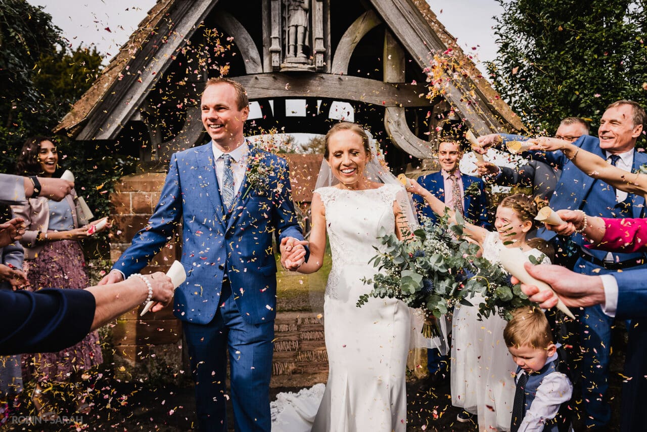 Guests throw confetti over bride and groom outside St Kenelm's church Romsley