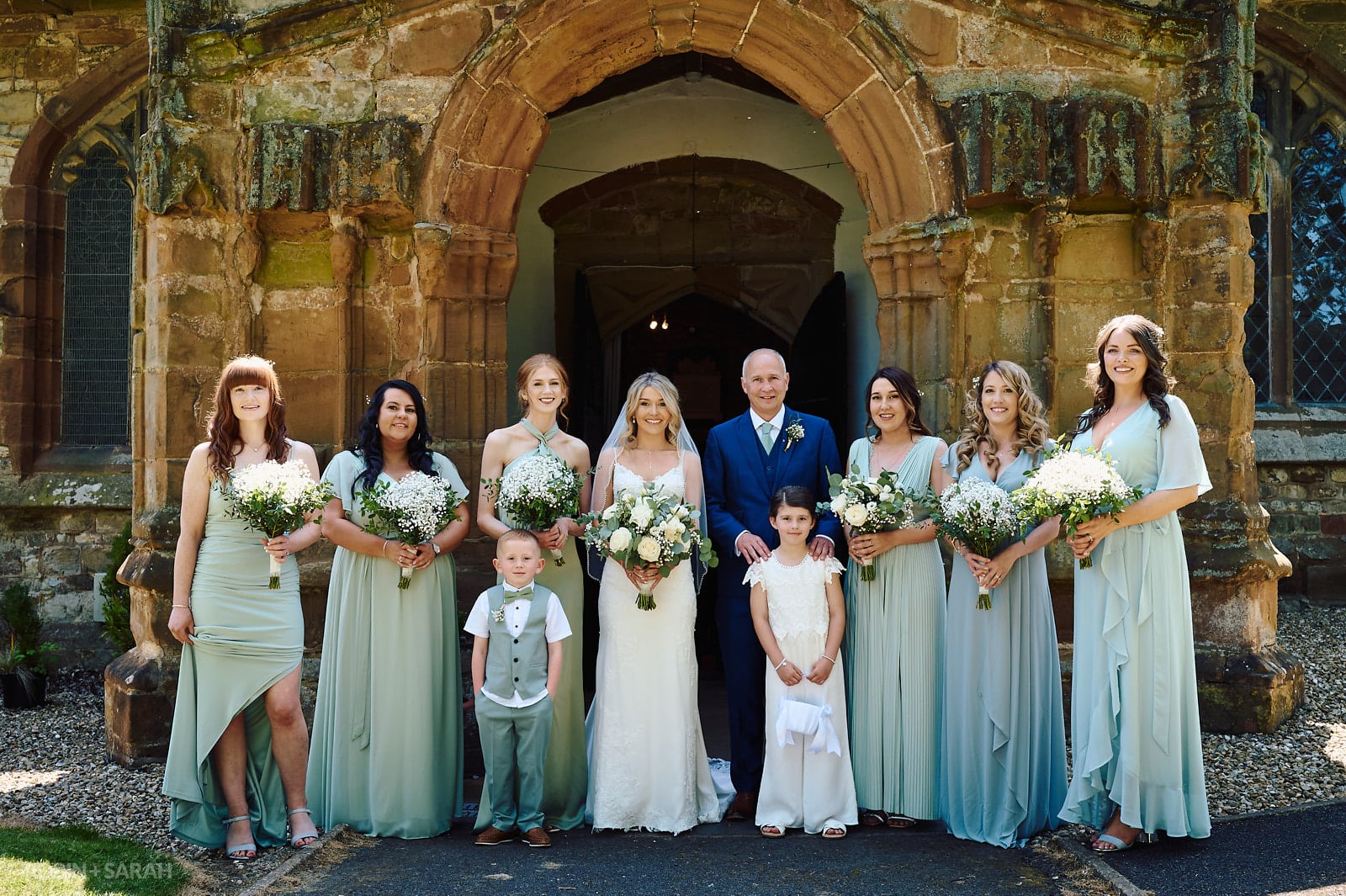Wedding group photo of bride, dad and bridesmaids outside St Botolph's church Newbold-on-Avon