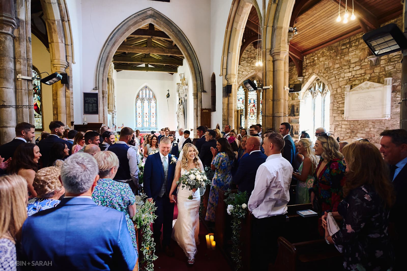 Bride and groom leave wedding ceremony at St Botolph's church Newbold-on-Avon