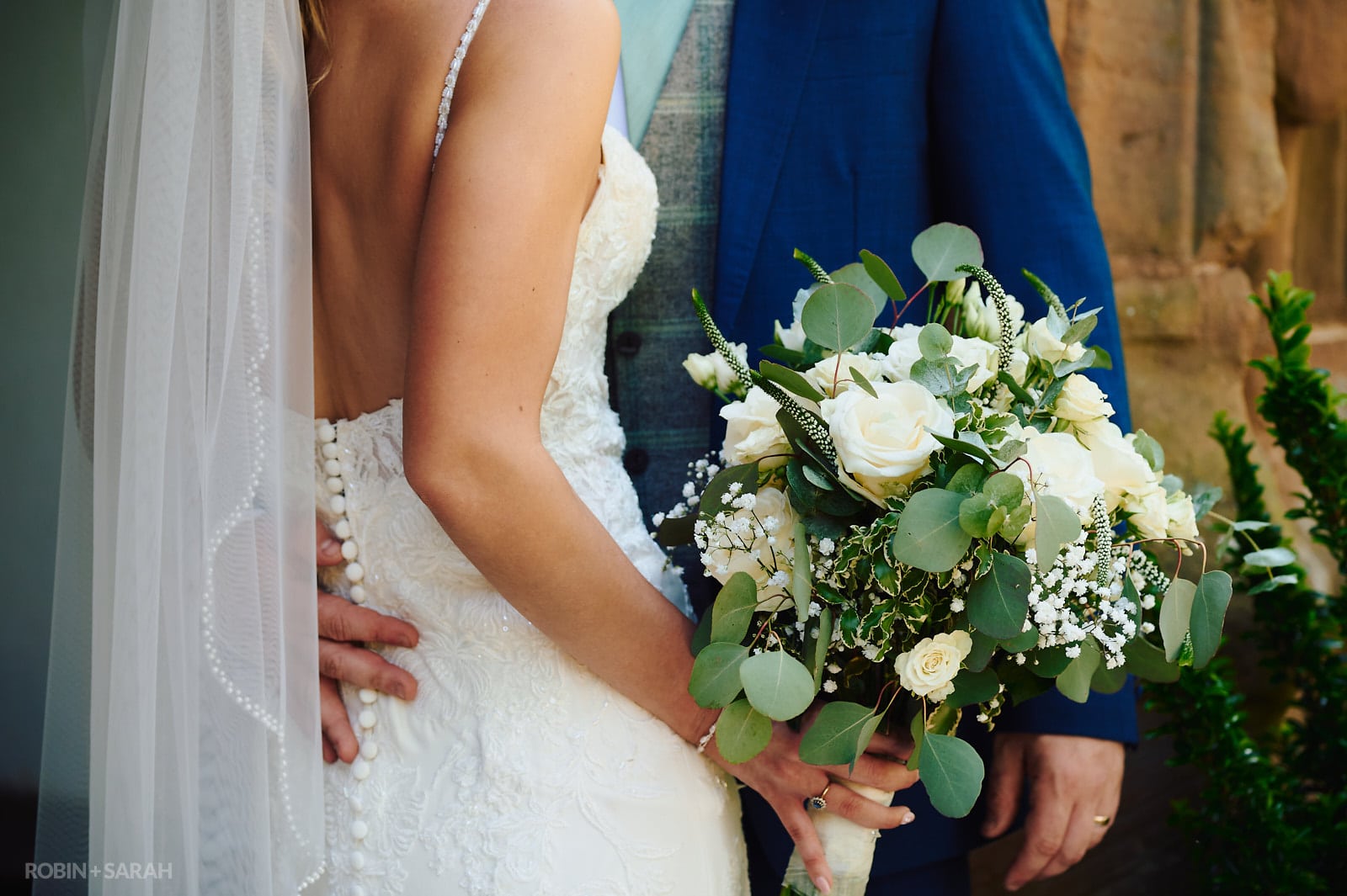 Detail of bride's wedding dress, veil and bouquet
