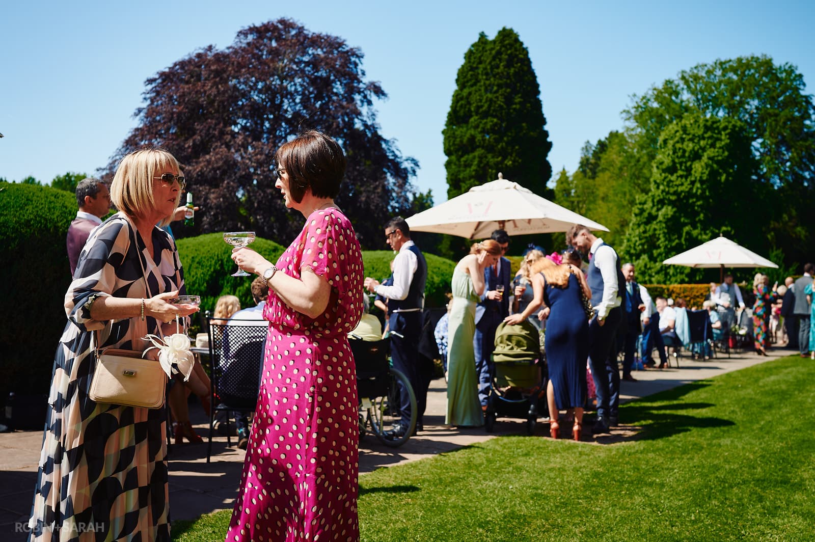 Wedding guests chat and relax on terrace at Coombe Abbey