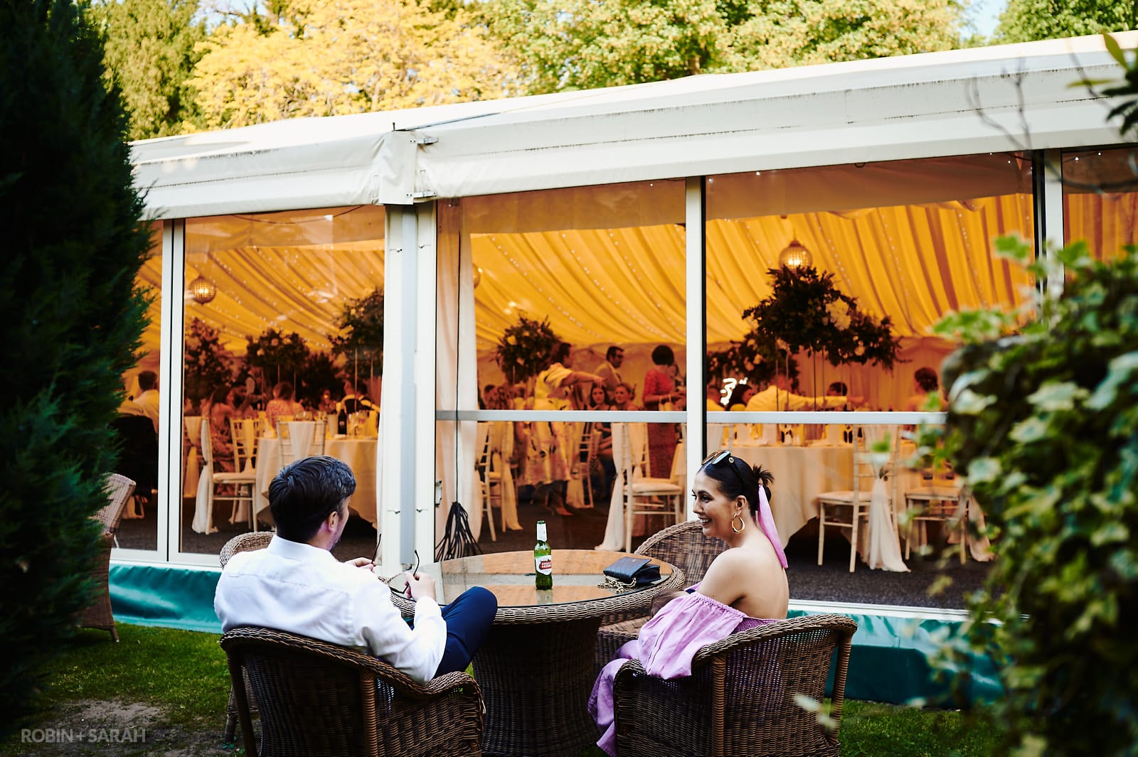 Wedding guest chat and relax outside marquee at Coombe Abbey