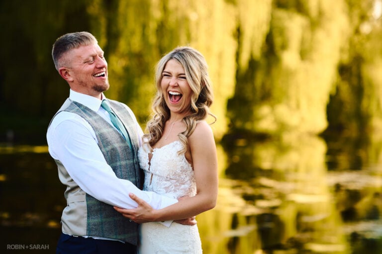 Bride and groom laughing together in grounds at Coombe Abbey