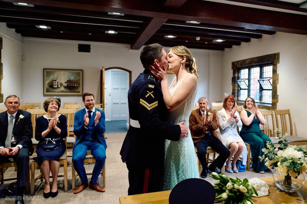 Bride and groom kiss during wedding ceremony in The Henley Room, Stratford-upon-Avon