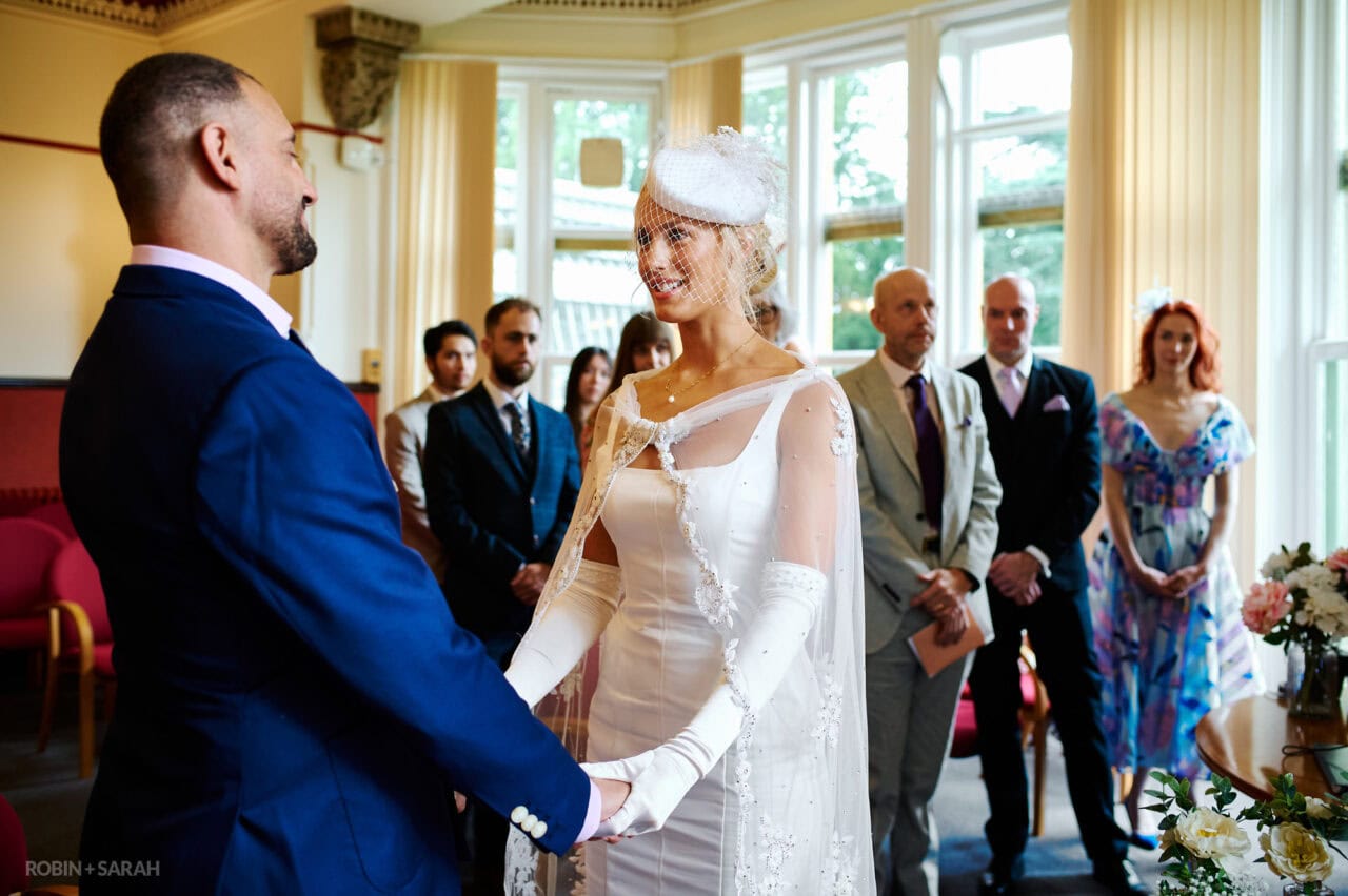 Bride and groom exchange wedding vows during ceremony in The Elgar Room as guests watch