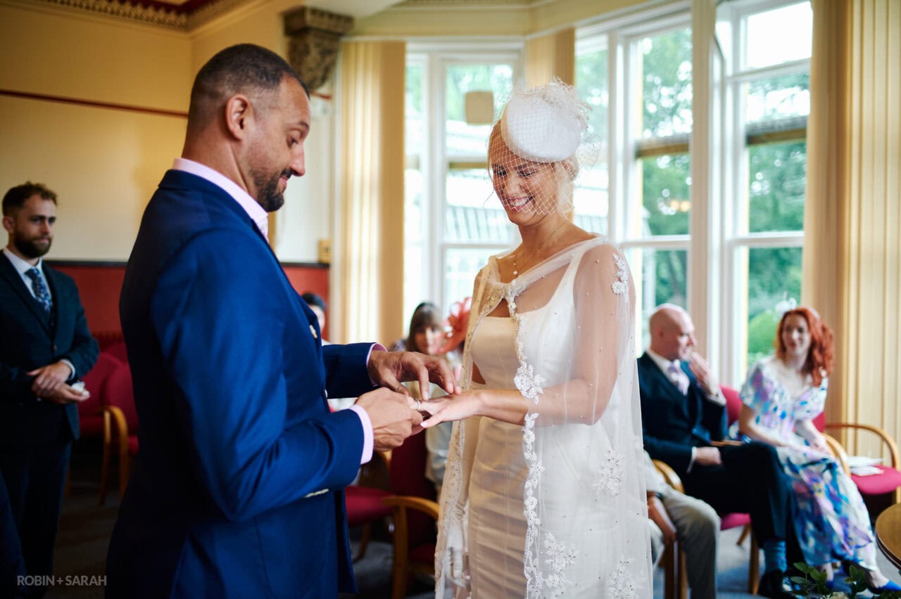 Bride and groom exchange wedding rings during ceremony at The Elgar Room in Malvern