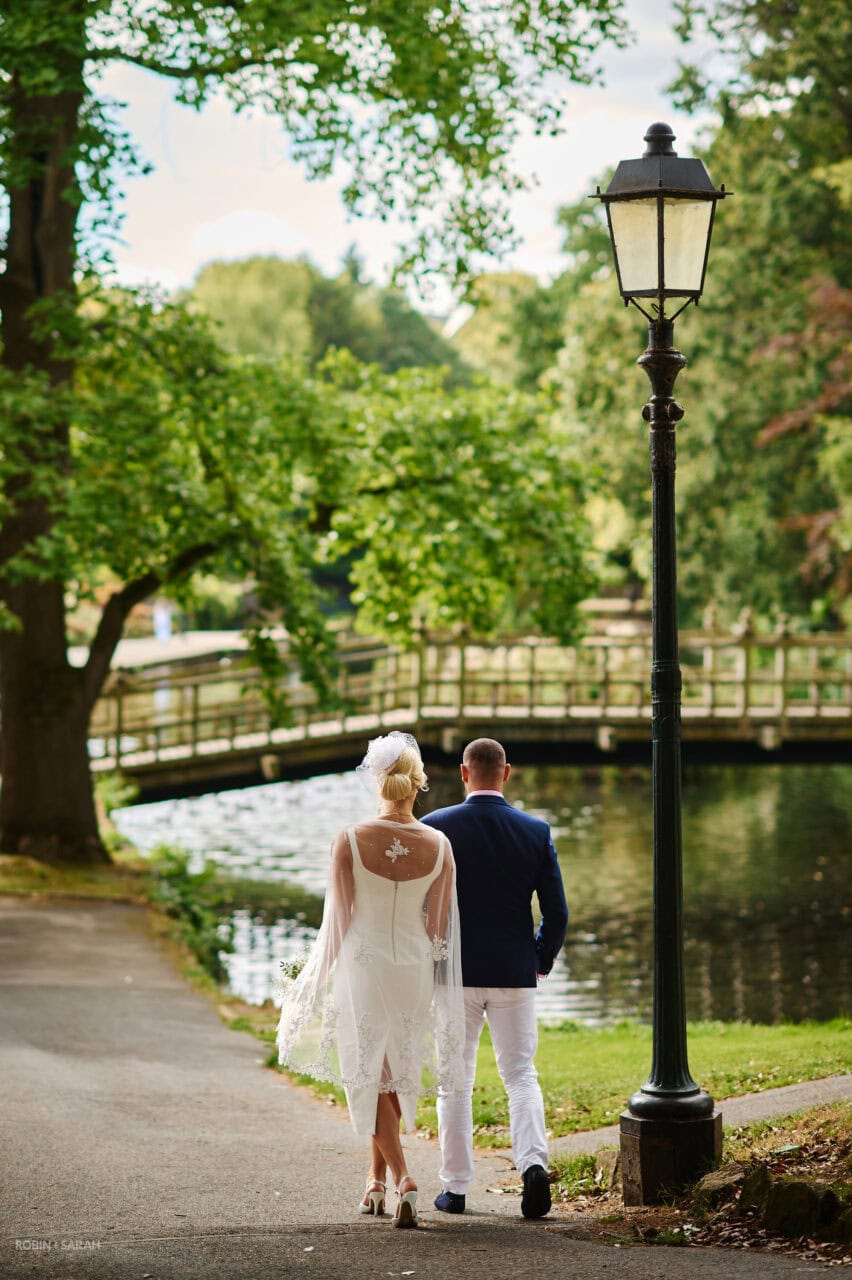 Bride and groom walk together into Priory Park in Malvern