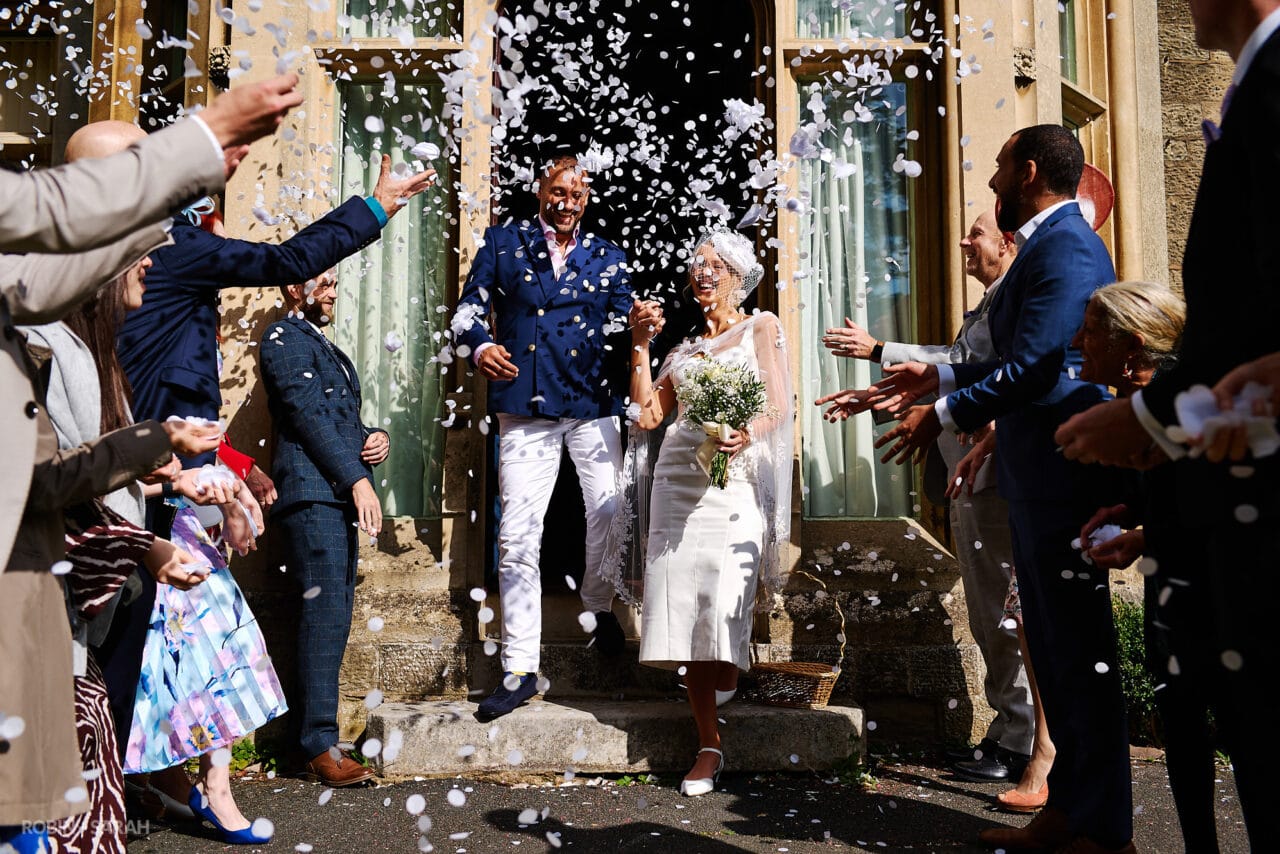 Bride and groom exit The Elgar Room as guests throw confetti over them