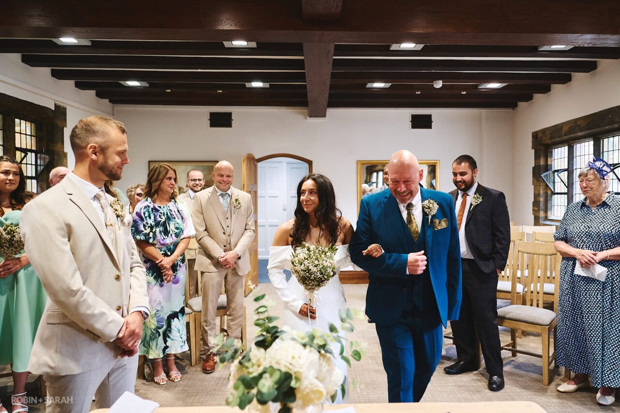 Bride and dad enter wedding ceremony as guests watch