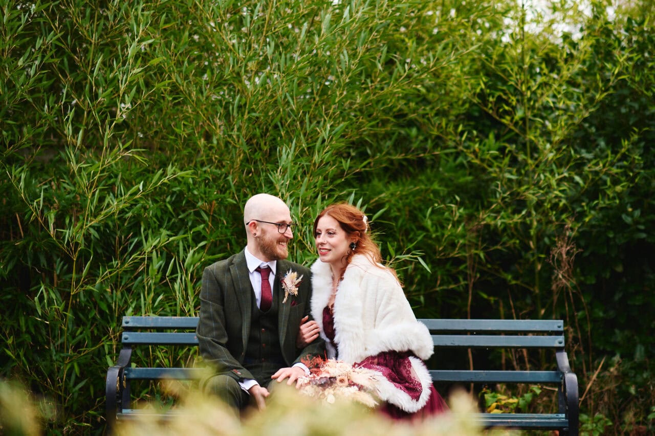 Bride and groom sitting on park bench