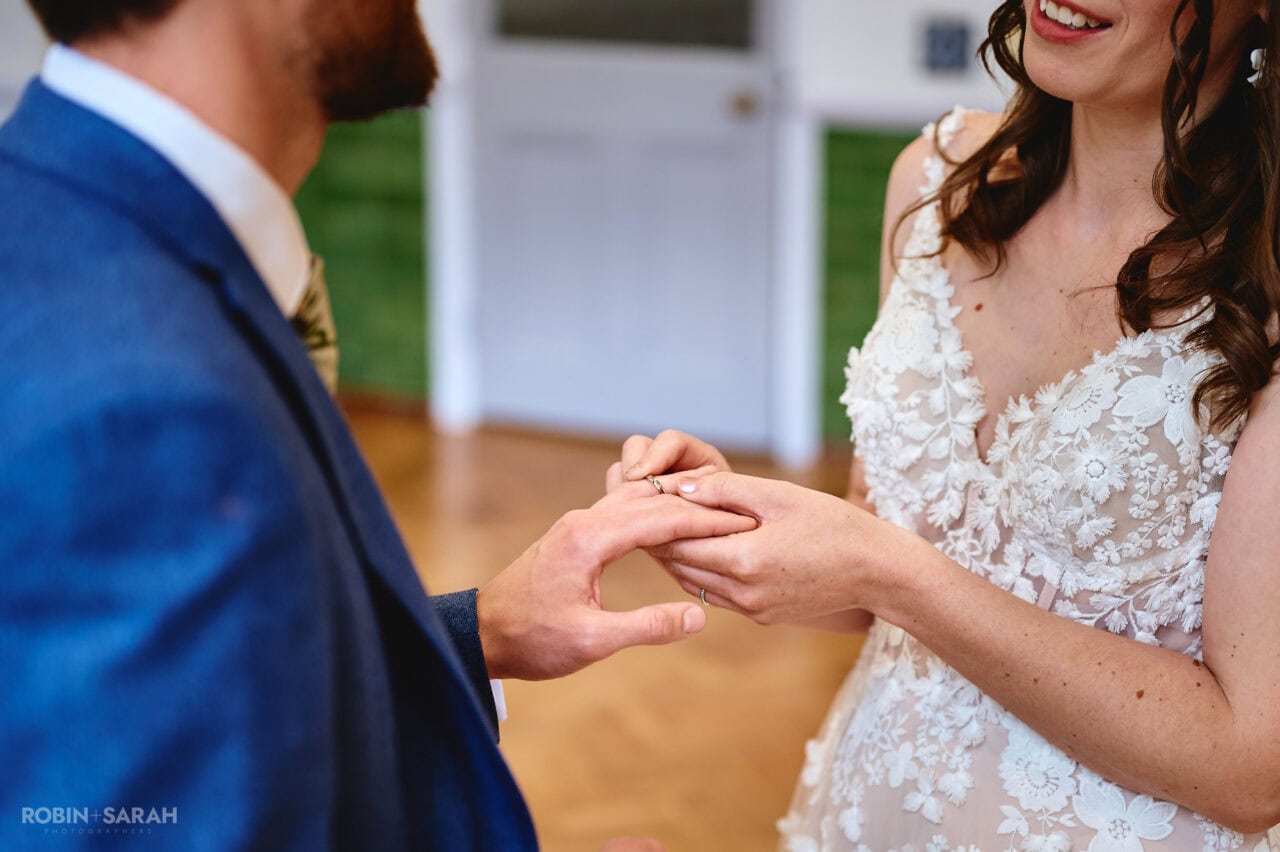 Bride places wedding ring on groom's finger