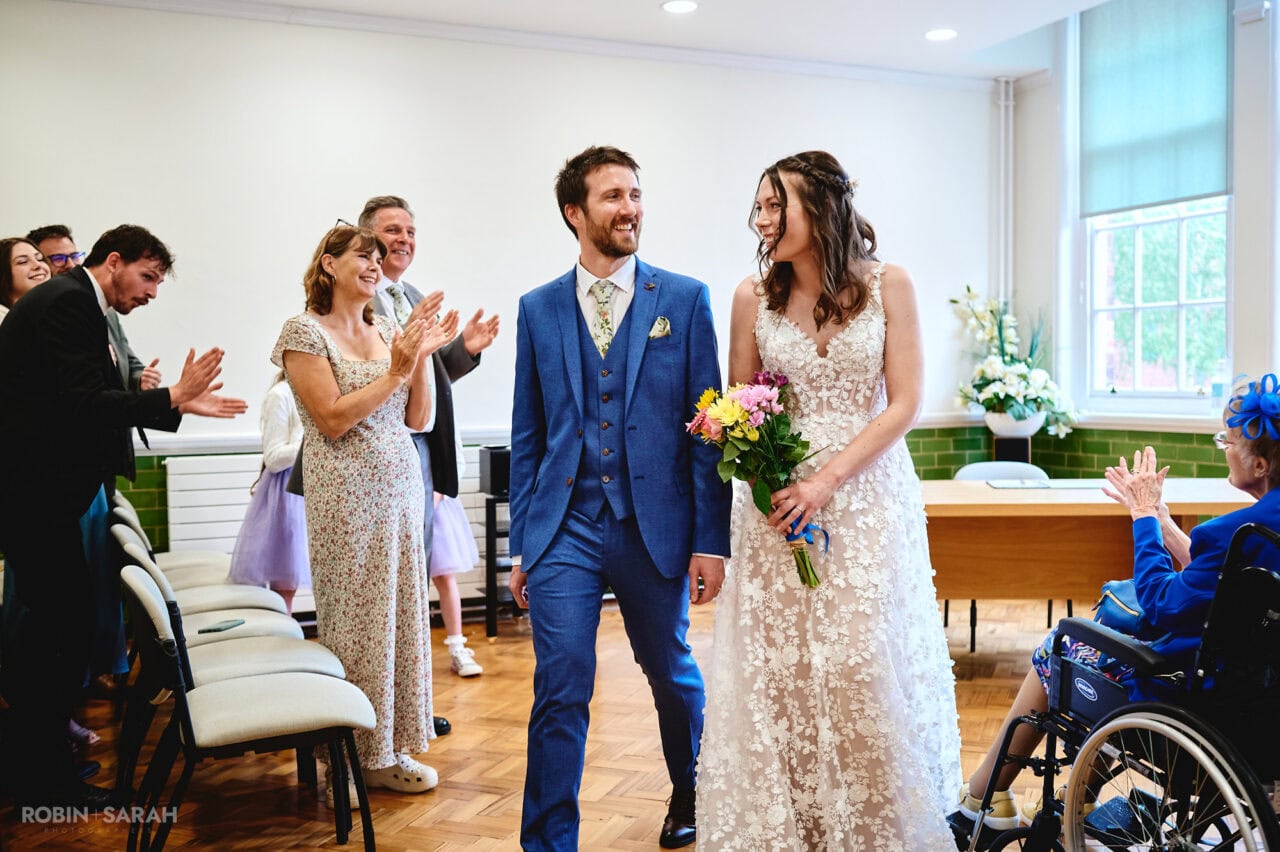 Bride and groom leave ceremony room at Bromsgrove Registration Office as guests clap
