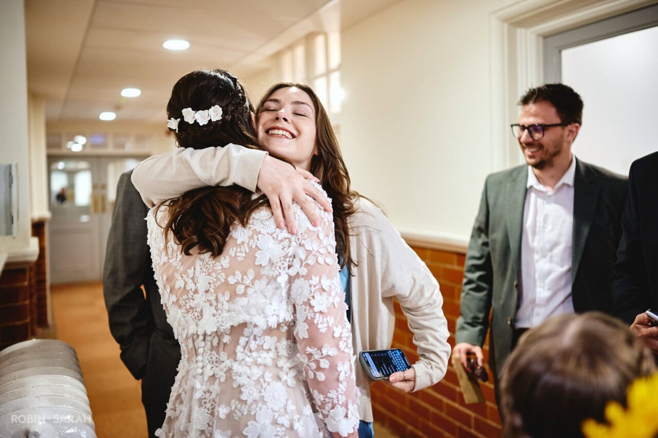 Wedding guests hug bride and groom after ceremony