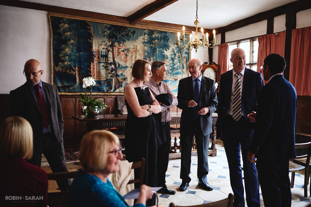Wedding guests chat and relax in the Great Hall at Greyfriars before ceremony begins