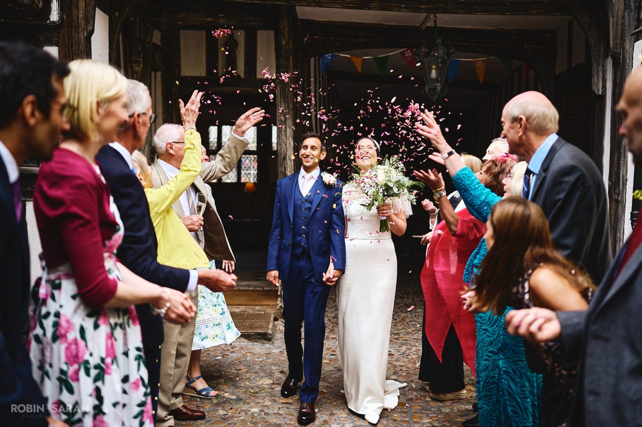 Bride and groom walk through wedding guests as they throw confetti