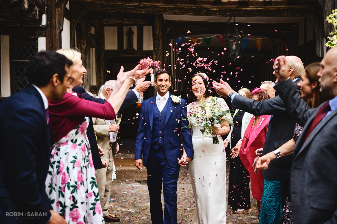 Bride and groom walk through wedding guests as they throw confetti