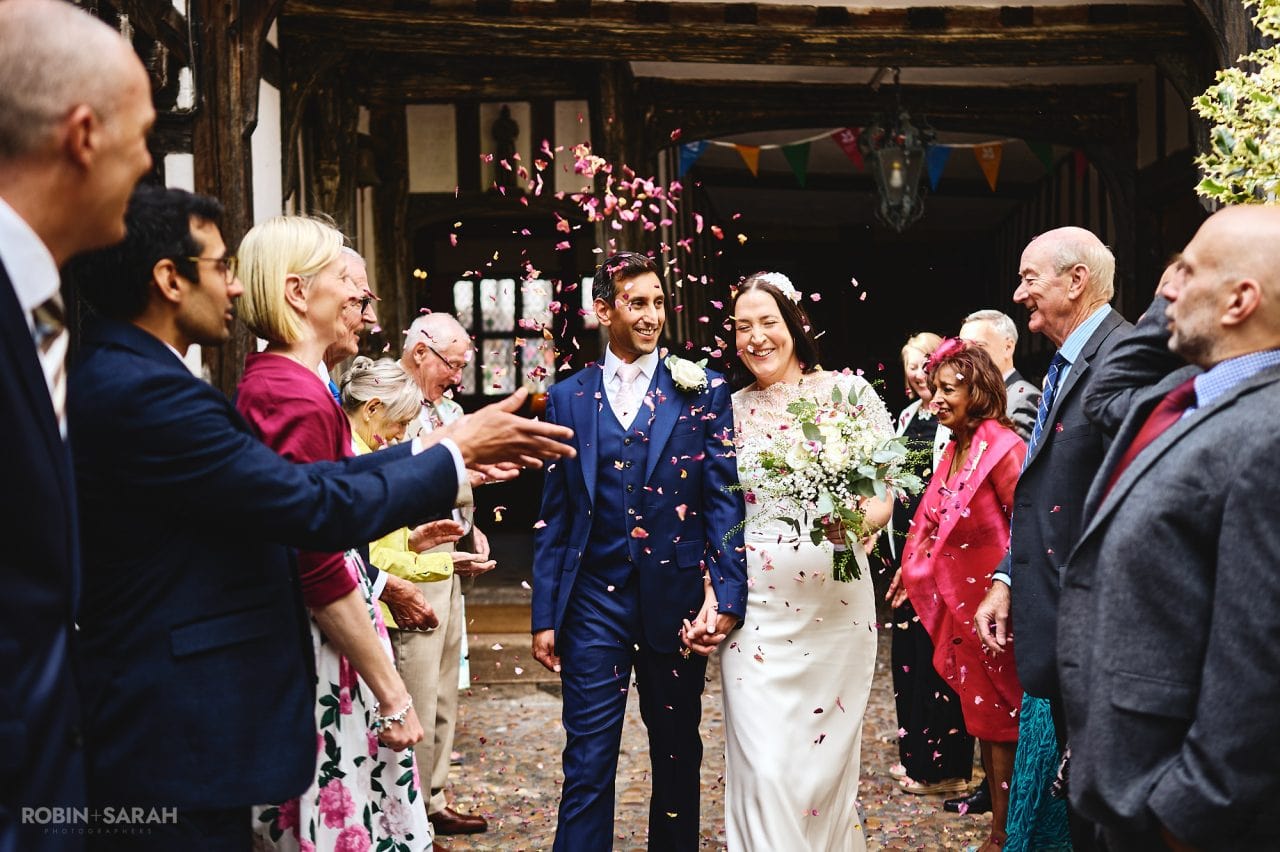 Bride and groom walk through wedding guests as they throw confetti