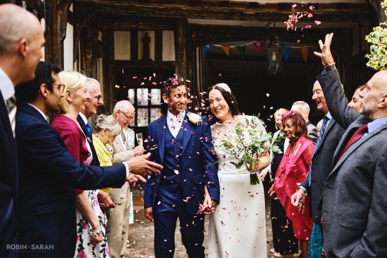 Bride and groom walk through wedding guests as they throw confetti