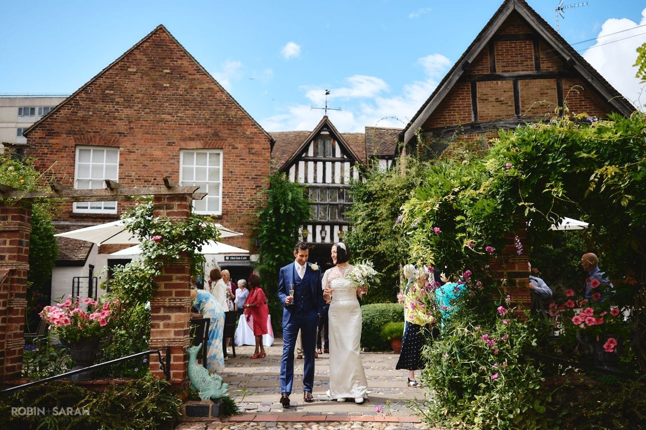 Bride and groom walk together in garden with Greyfriars house in background