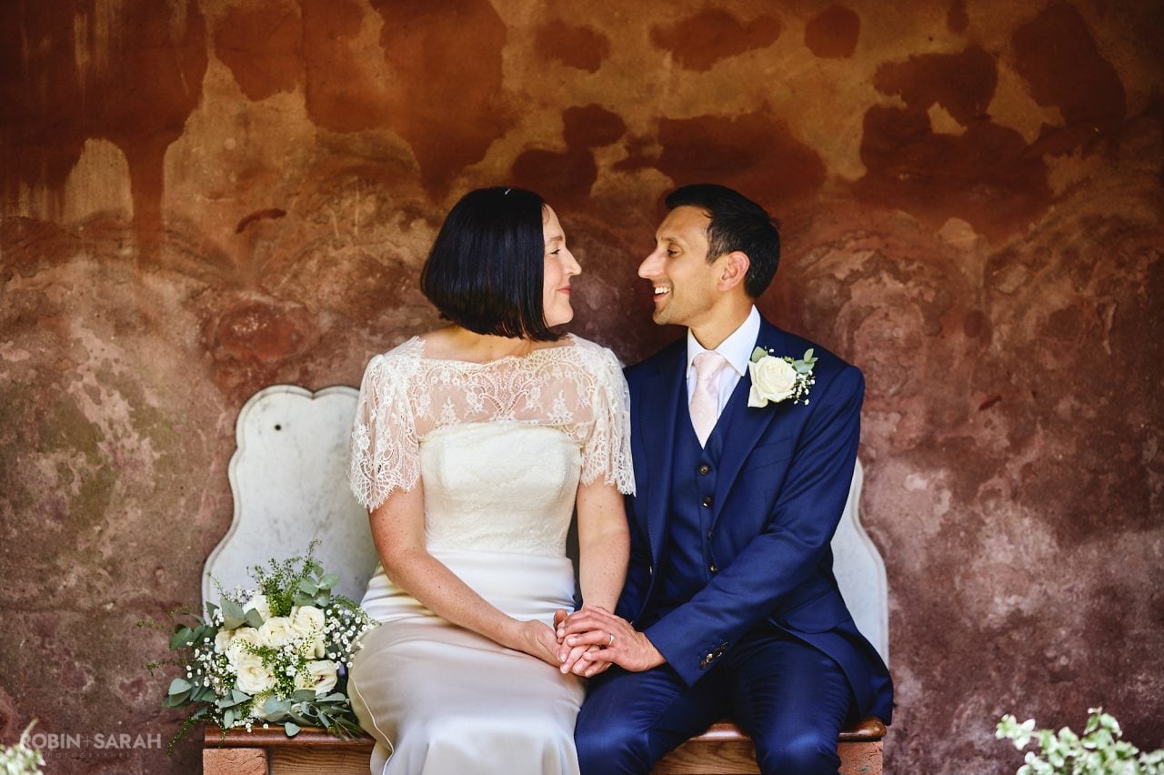 Bride and groom sitting on bench and holding hands