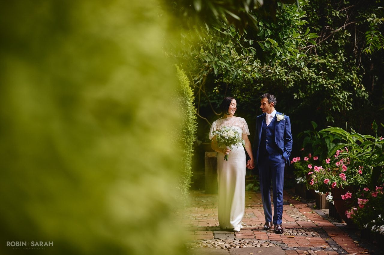 Bride and groom walking hand in hand through beautiful gardens
