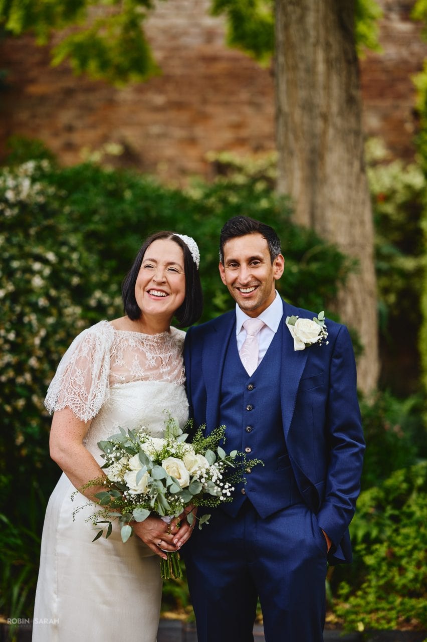 Bride and groom laughing together in gardens