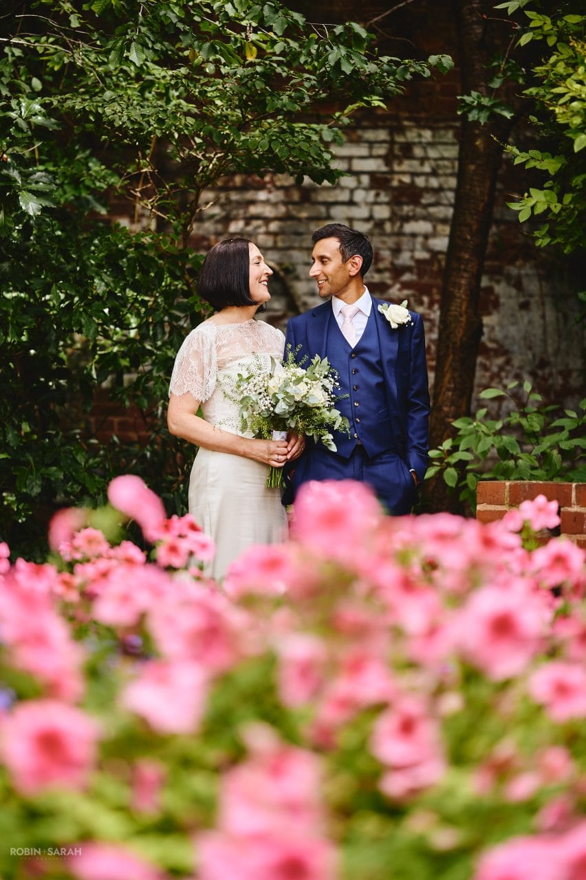 Bride and groom in garden at Greyfriars surrounded by trees and pink flowers