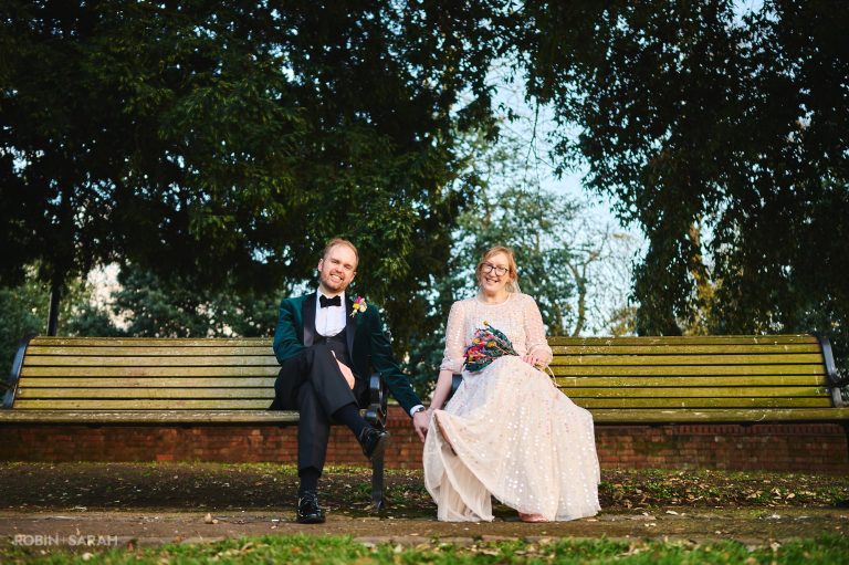 Bride and groom sit on bench in Firs Garden, Stratford-upon-Avon