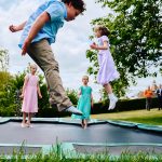 Four kids playing on a trampoline at a small wedding held in a garden
