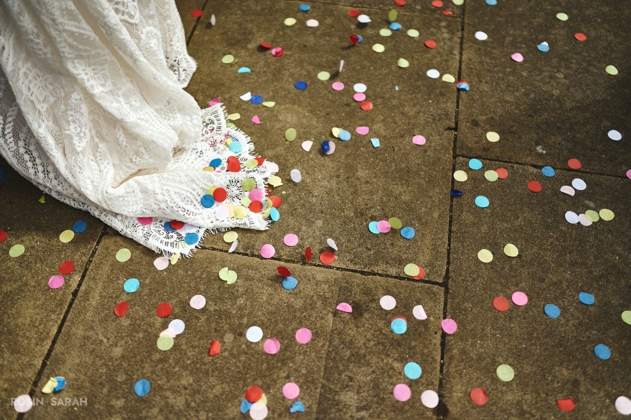 Coloured confetti on paving slabs with bride's dress