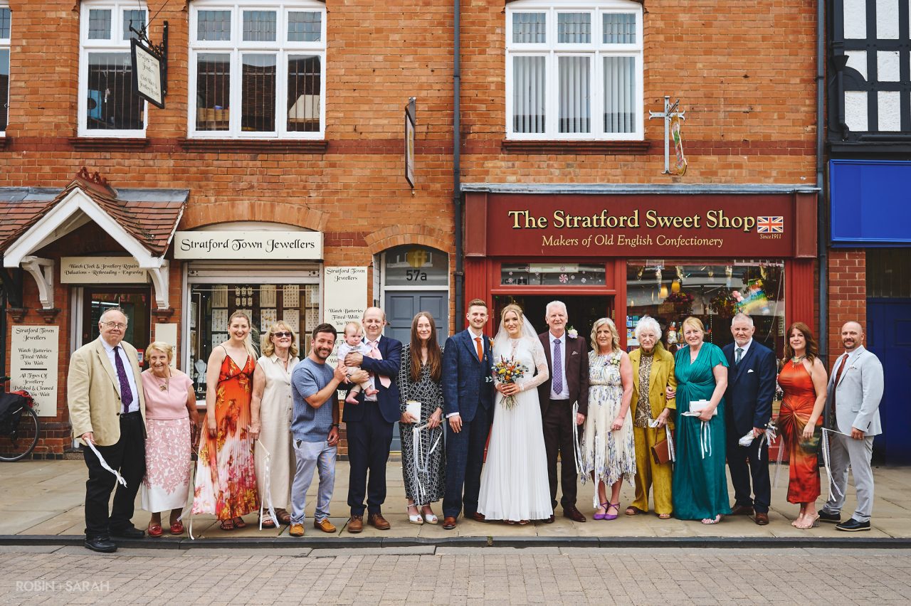 Wedding group photo on the street outside The Henley Room, with shops behind them