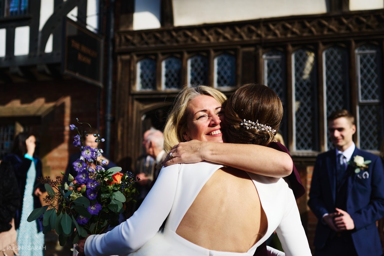 Wedding guest hugs bride outside The Henley Room as the sun shines on her face