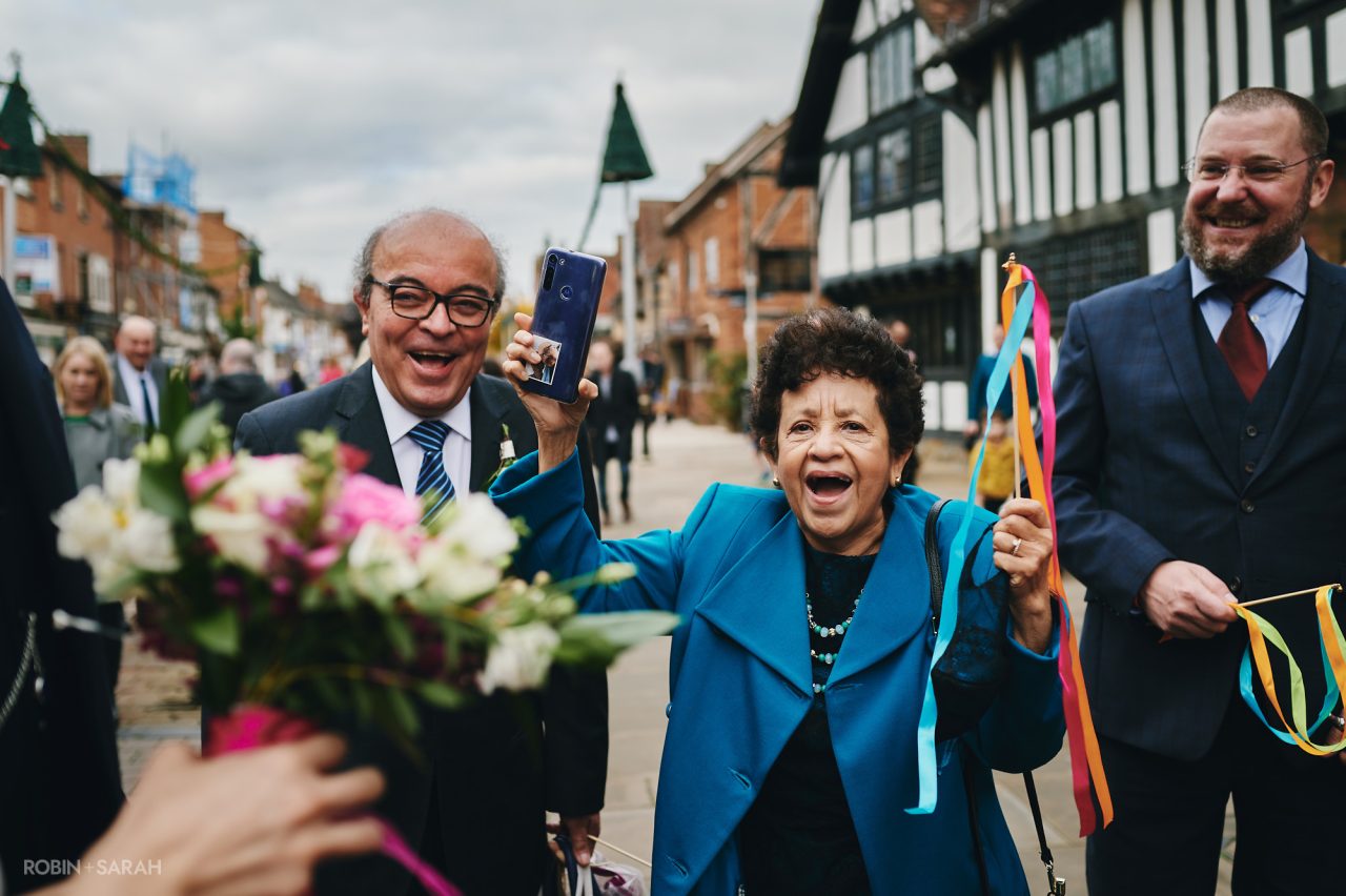 Wedding guests cheer the couple and wave ribbon wands outside The Henley Room in Stratford-upon-Avon