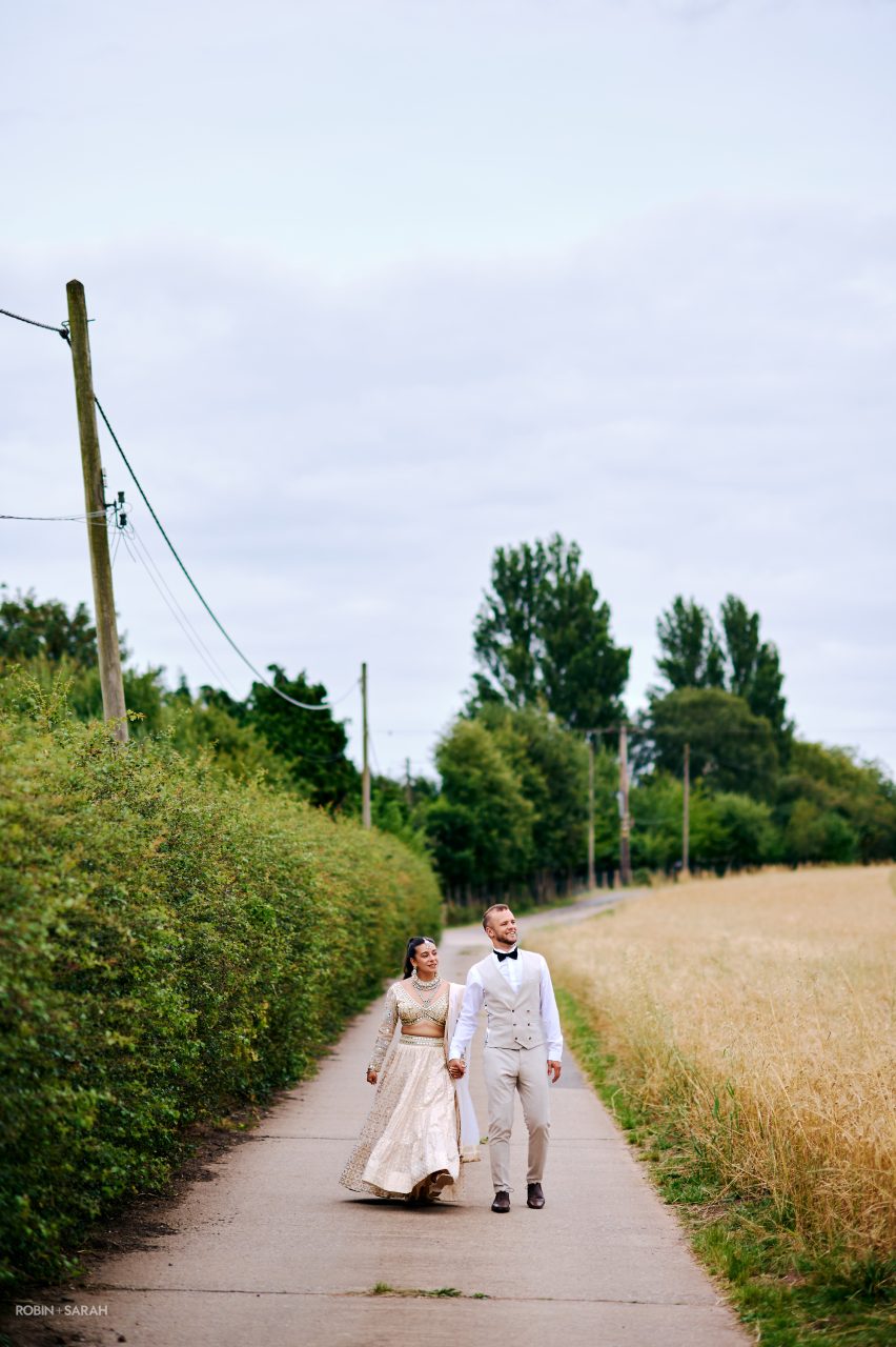 Bride and groom walk down country lane at Old Rail Farm near Atherstone, Warwickshire