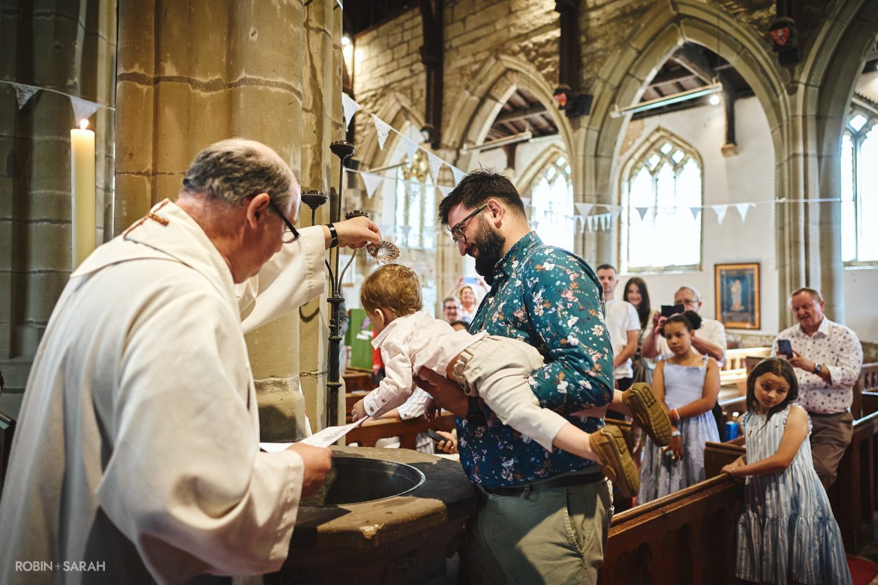Vicar baptises child at St John the Baptist Church in Brinklow