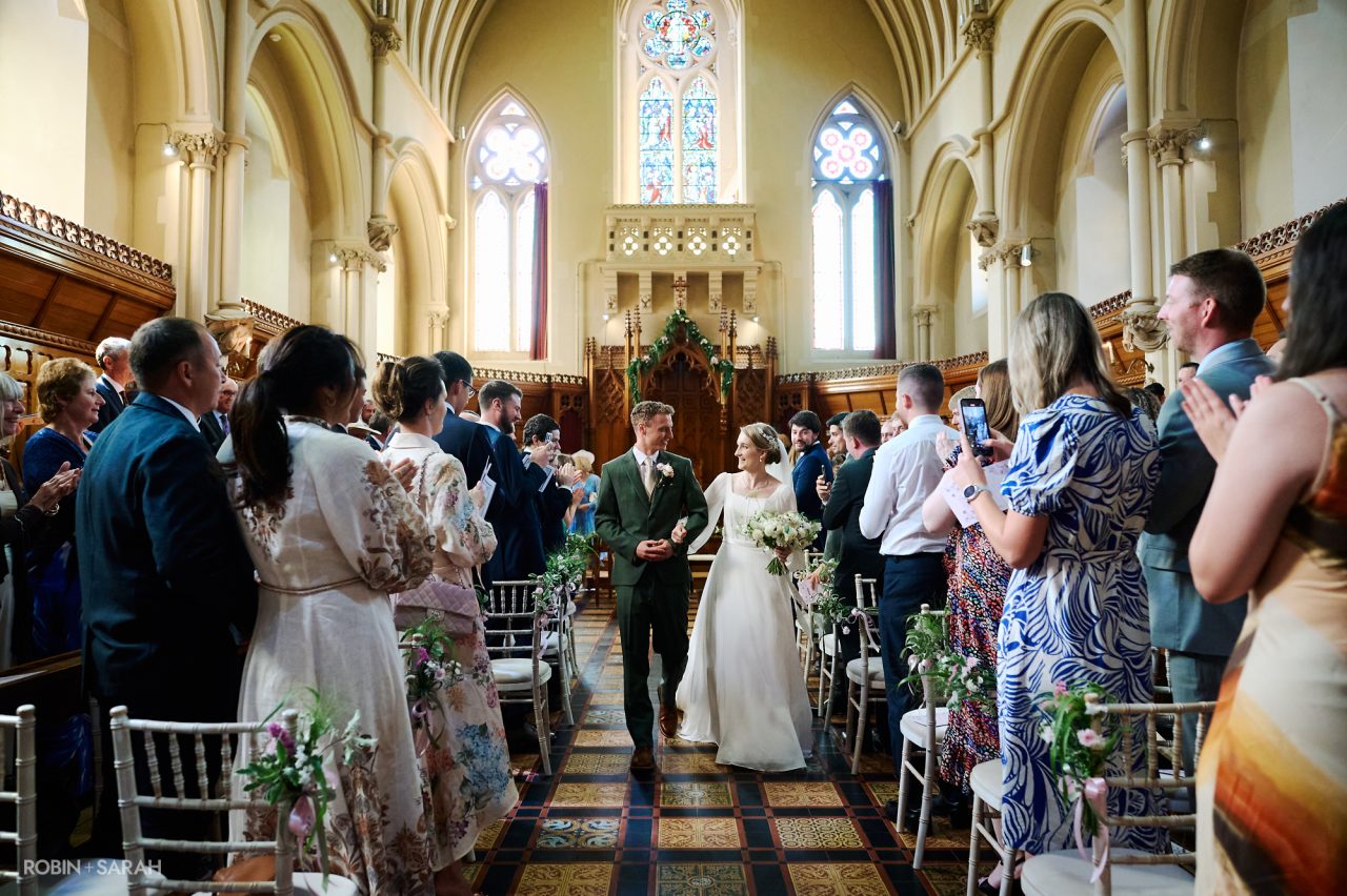 Bride and groom leave wedding ceremony at Stanbrook Abbey near Malvern, Worcestershire