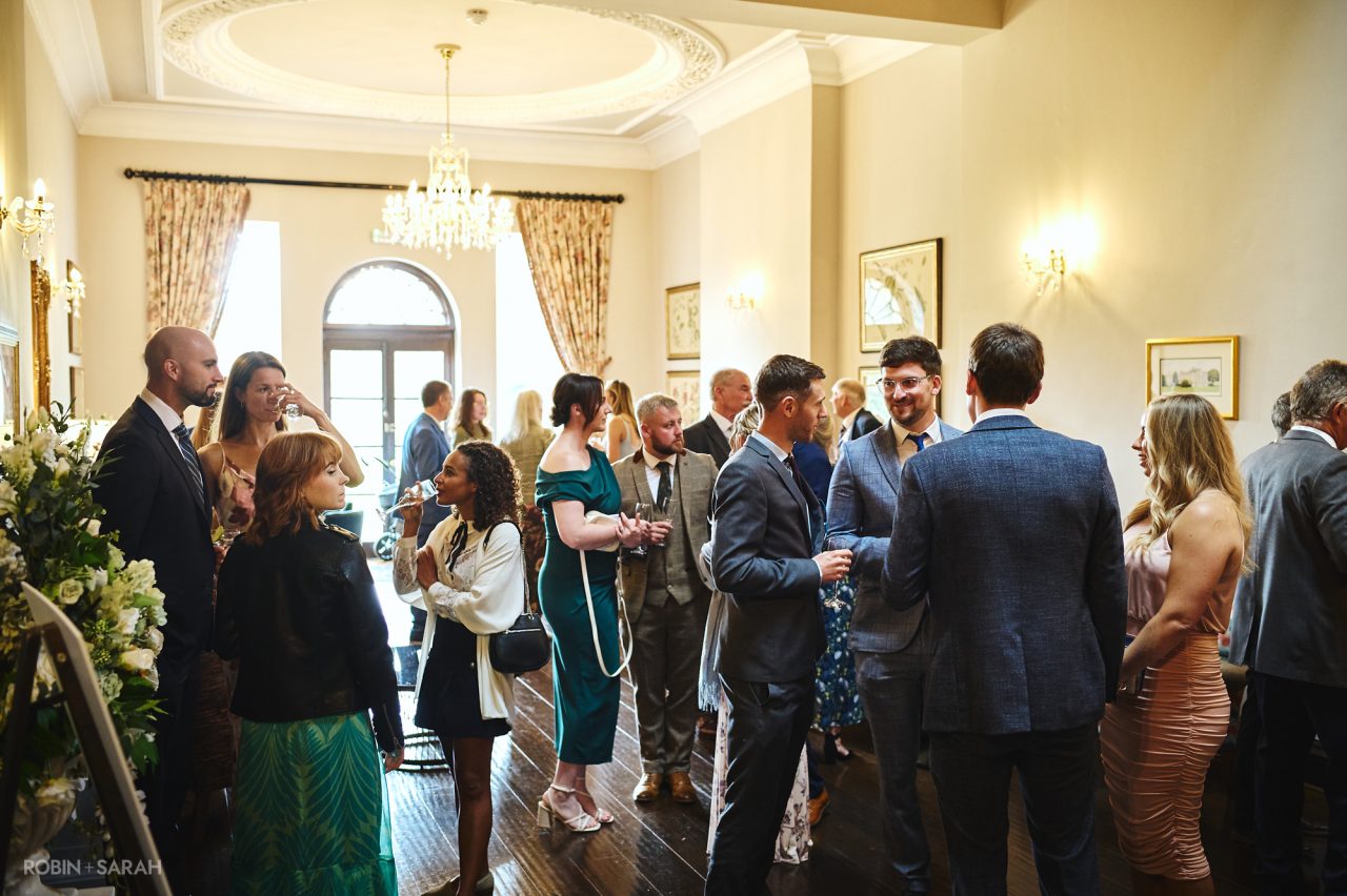 Wedding guests chat and relax during drinks reception at Bourton Hall