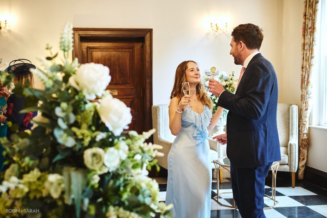 Bridesmaid chats with partner during wedding drinks reception at Bourton Hall