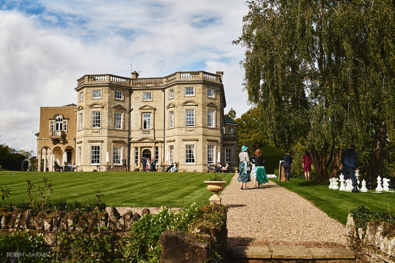 View of Bourton Hall with wedding guests playing lawn games and relaxing in the afternoon sunshine