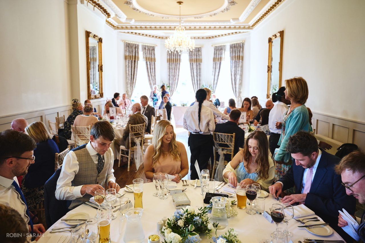 Wedding guests taking seats for meal in Banqueting Hall at Bourton Hall