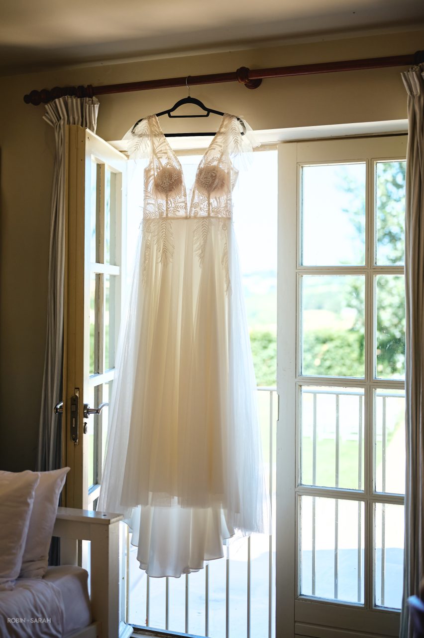 Wedding dress hanging in window at Charingworth House