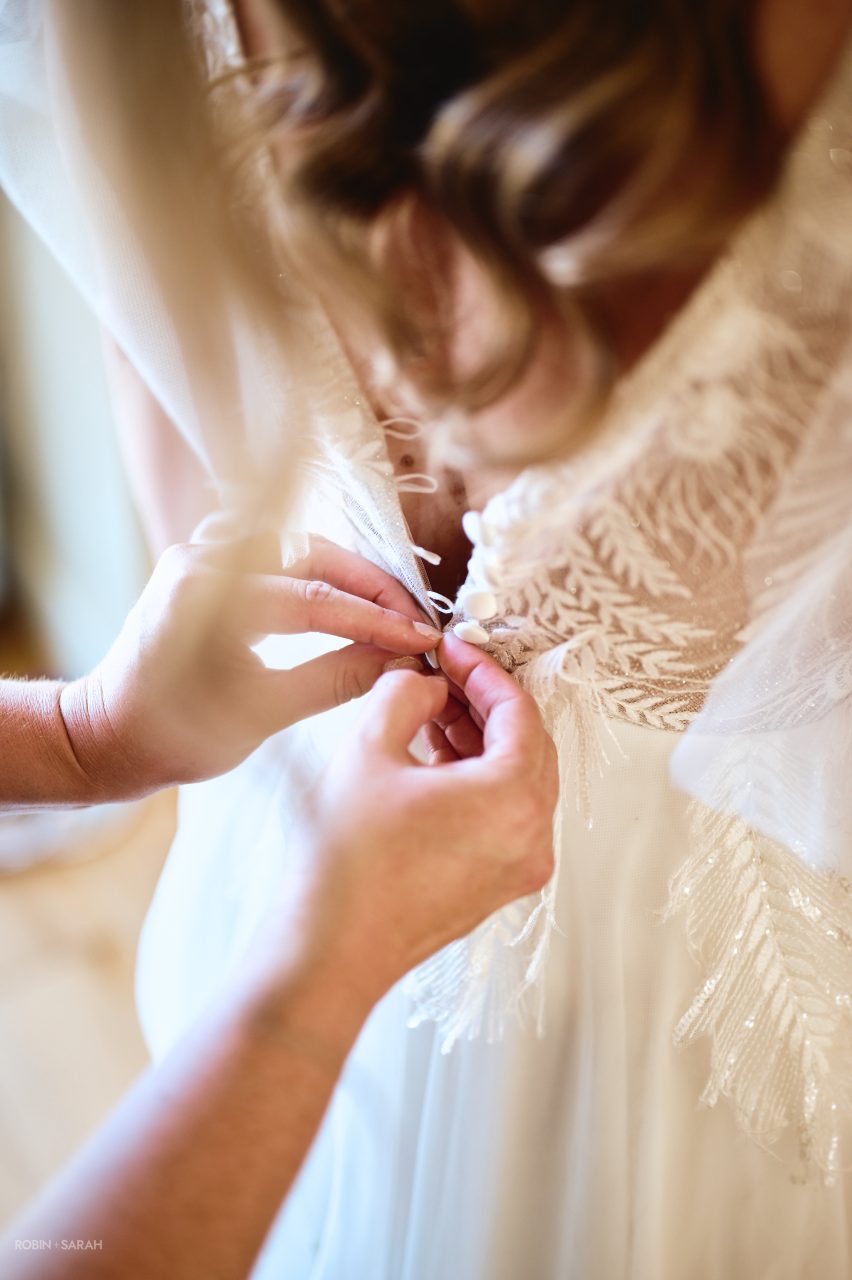 Bride has wedding dress fastened